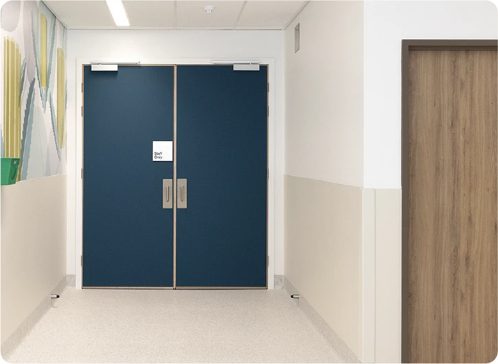 Hallway with beige walls, brown non rated door right and blue “Exit Only” doors in center. Solid Core Doors.