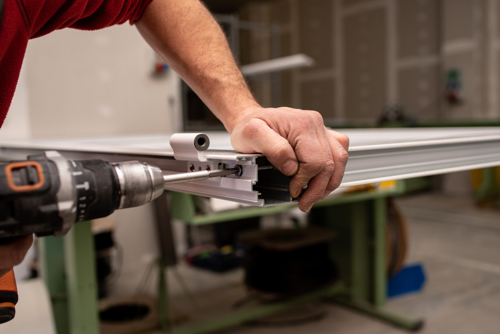 A worker uses a power drill for fire door maintenance on a metal door frame at the bf door manufacturing facility.
